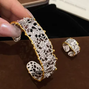 Dettaglio del bracciale rigido vintage in argento traforato con bordi dorati e pietre.