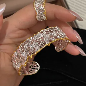Primo piano di un bracciale vintage traforato in argento e oro con cristalli luminosi.