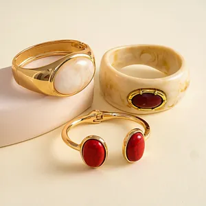 Detailweergave van vintage hars armbanden met ovale steeninleg in goud- en crèmetinten.