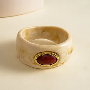 Detailweergave van een vintage marmeren hars armband met rode ovale edelsteen