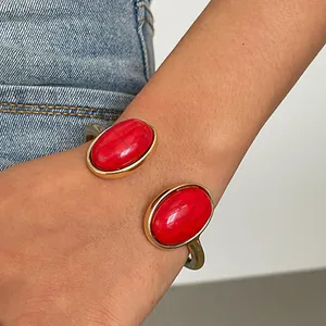 Detailweergave van een vintage goudkleurige manchetarmband met rode marmeren stenen.