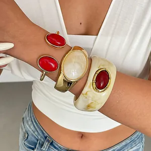 Detailopname van vintage marmeren hars en gouden ovale armbanden om de pols van model
