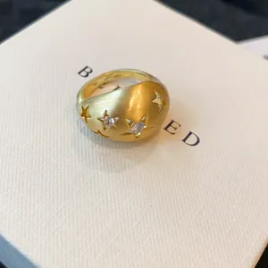 Gedetailleerde opname van een gouden ring met sterpatronen en glanzende zirkoonstenen