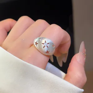 Detailopname van een geborstelde metalen ring met steruitsparingen en een zirkonsteen.