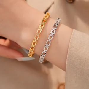 Close-up van elegante 18K goud en zilver vergulde zirkoon dubbele C-schakelarmbanden