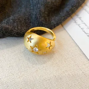 Detailweergave van geborsteld gouden ring met steruitsnijdingen en glimmend zirkoon