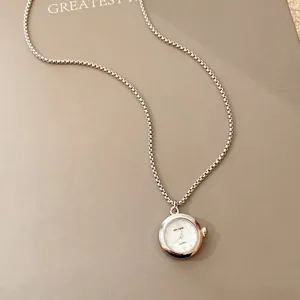 Détail élégant d'un collier pendentif montre ronde en argent avec une chaîne box