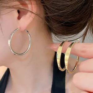 Nahaufnahme minimalistischer Gold- und Silber-Creolen mit glattem Hochglanz-Finish