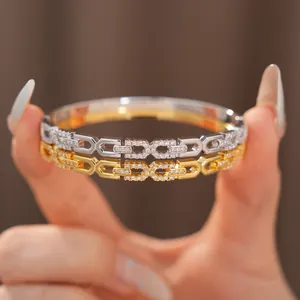 Detailweergave van 18K vergulde zirkoon armbanden met in elkaar grijpende schakels.