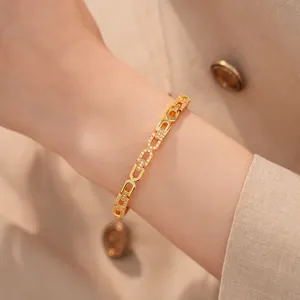 Detailweergave van een elegante 18K vergulde schakelarmband met zirkonia op een pols