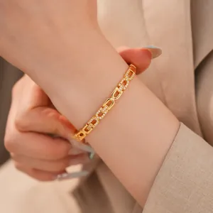 Gedetailleerd overzicht van een 18K vergulde zirkoon schakelarmband om de pols
