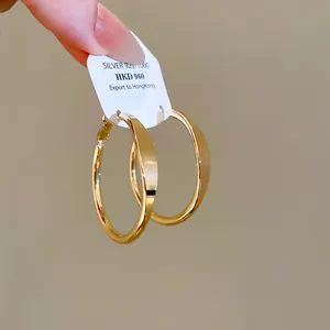 Makro-Detailansicht glänzender goldener Creolen mit 925er Silber-Zertifikat