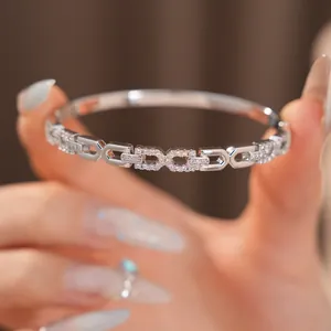 Close-up van een zilverkleurige armband met in elkaar grijpende schakels en zirkonia's.