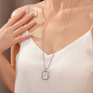 Vue détaillée d'un collier pendentif montre de poche carré argenté sur un modèle.