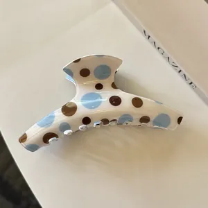 Nahaufnahme einer stylischen Haarklammer aus Acryl mit blauen und braunen Punkten.