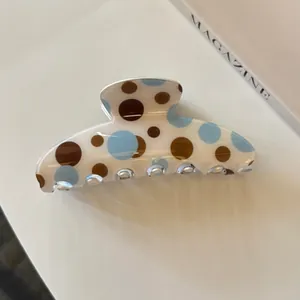 Nahaufnahme einer eleganten Haarklammer aus Acryl mit braun-blauen Polka-Dots Muster.