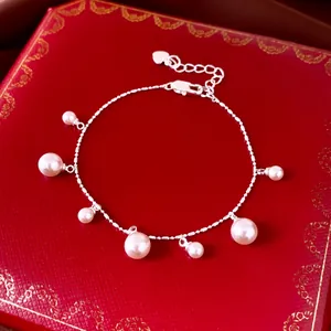Elegant silver pearl tassel bracelet featuring seven round charms on red jewelry box