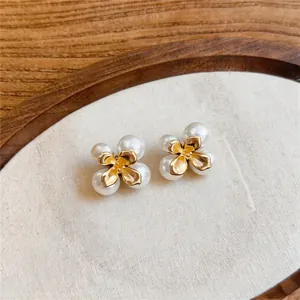 Detailopname van elegante Franse stijl bloem pareloorbellen met gouden bloemblaadjes.