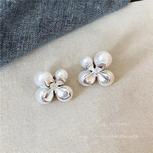 Detailweergave van elegante bloemvormige oorbellen met witte parels en zilver metaal.