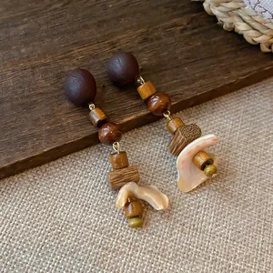 Macro view of vintage earrings with wooden beads and natural shell petals on wood.