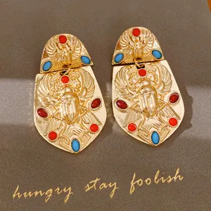 Detaillierte Nahaufnahme von Vintage-Gold-Skarabäus-Ohrringen mit rot-blauen Edelsteinen
