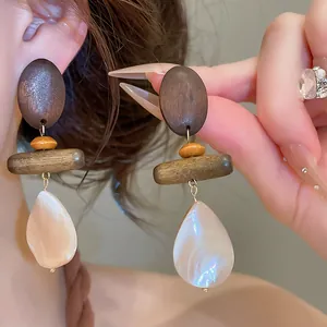 Detailed view of retro wooden earrings with pearlescent shell teardrop pendants