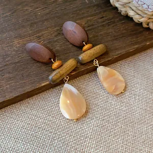 Detailed view of handmade wood and shell drop earrings with retro aesthetic on a rustic surface