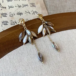 Close-up view of elegant vintage shell petal drop earrings with hammered gold studs