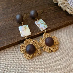 Detailed shot of raffia flower earrings with wooden beads and iridescent shell tiles