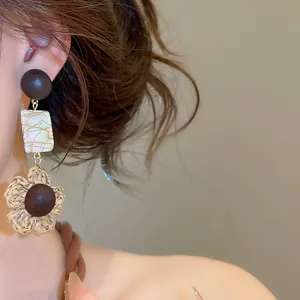 Elegant retro earrings with pearlescent shell beads and woven raffia flower detail on model