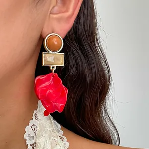 Detailansicht eines Vintage-Acrylohrrings mit großem rotem Blütenblatt und Perlen.
