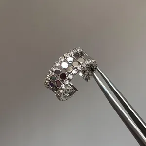 Gros plan détaillé d'une bague ouverte avec motifs en nid d'abeille tenue par une pince