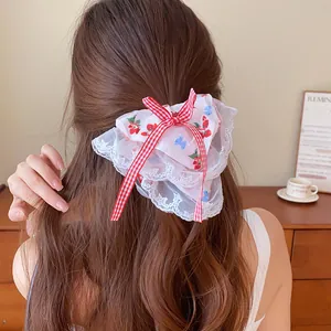 Detail van een grote bloemenkant scrunchie met een rood geruit strikje op bruin haar