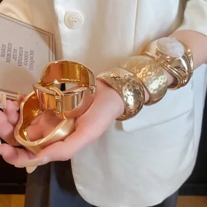 Detailed view of fashionable textured gold chunky bracelets and white resin inlay