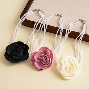 Detailed view of three layered pearl necklaces featuring black, pink, and white fabric roses.