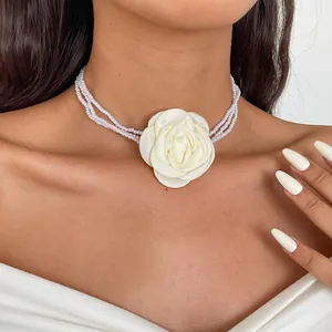 Detail of multi-strand pearl choker featuring a large white fabric rose centerpiece