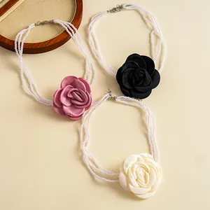 Close-up of multi-layer pearl necklaces featuring pink, black, and white fabric flower charms