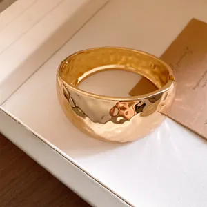 Macro detail of wide gold hammered texture cuff bracelet for fashion jewelry design