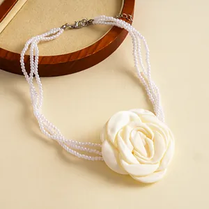 Detail of vintage multi-strand pearl necklace with large white fabric rose flower