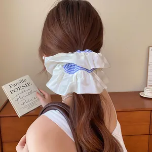 Achteraanzicht van een grote witte satijnen scrunchie met blauwe strepen in een staart