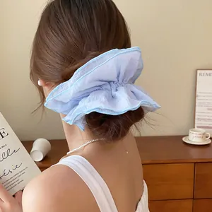 Detail van een grote lichtblauwe kanten scrunchie gedragen in een volumineus kapsel