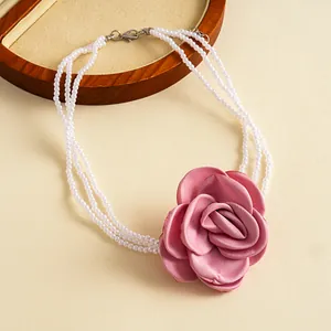 Close-up detail of vintage pink fabric rose and multi-layered white pearl strand necklace