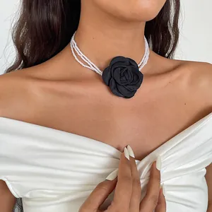 Close-up of a vintage triple-strand pearl choker necklace featuring a large black fabric rose