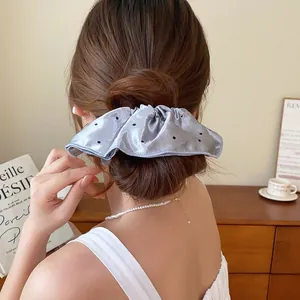 Detailopname van een lichtblauwe stoffen scrunchie met stippen op een knotje