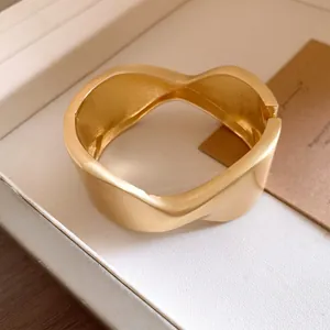 Macro detail of elegant matte gold wrinkled cuff bracelet with a unique wavy textured design