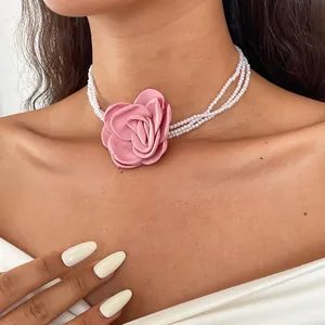 Close-up detail of a retro multi-strand pearl choker necklace with a large pink fabric rose