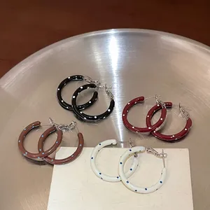 Detailed view of four pairs of colorful polka dot enamel hoop earrings on a metal tray