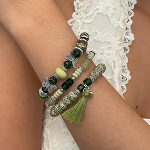 Dettaglio di braccialetti con perline verdi bohémien con ciondoli a farfalla e nappina
