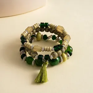 Primo piano dei braccialetti con perline di vetro e acrilico verde e nappa di seta
