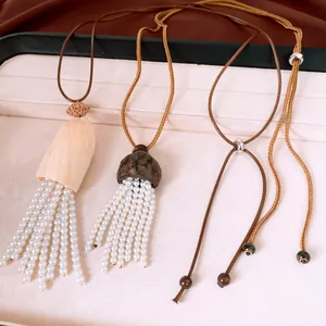Detailed view of leather cord necklaces with nut shell pendants and white pearl tassels